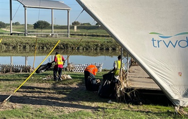 Cleaning up the trash near a river in Fort Worth after 2022 flooding.