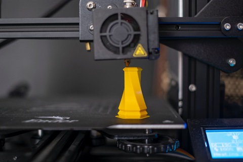 3D printer printing a yellow geometric object