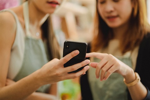 Two people gathered around a mobile phone