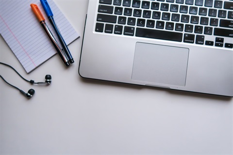 desk with markers, notepads and a laptop