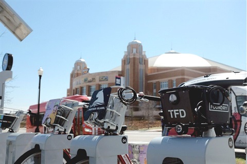 a bike share station with dickies arena in the background