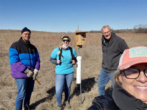 volunteers take a group selfie in front of a bluebird house