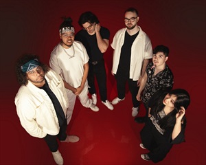 Members of Amplify 817 band Cherry Mantis stand in a semi-circle. The image background is a dark red. There are 5 members, and they're wearing black and white clothing.