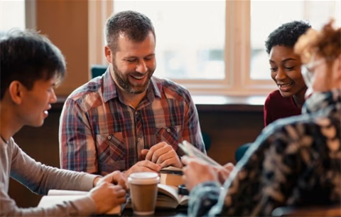 adults sitting around a table reading and laughing