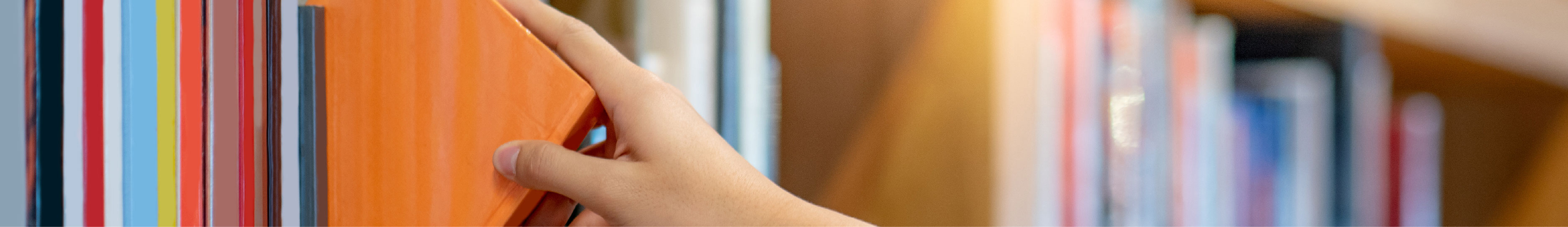 A photo of a person's hand pulling a book off a shelf.