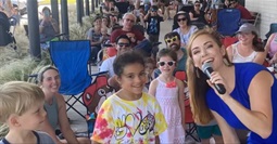 woman singing with children outside library