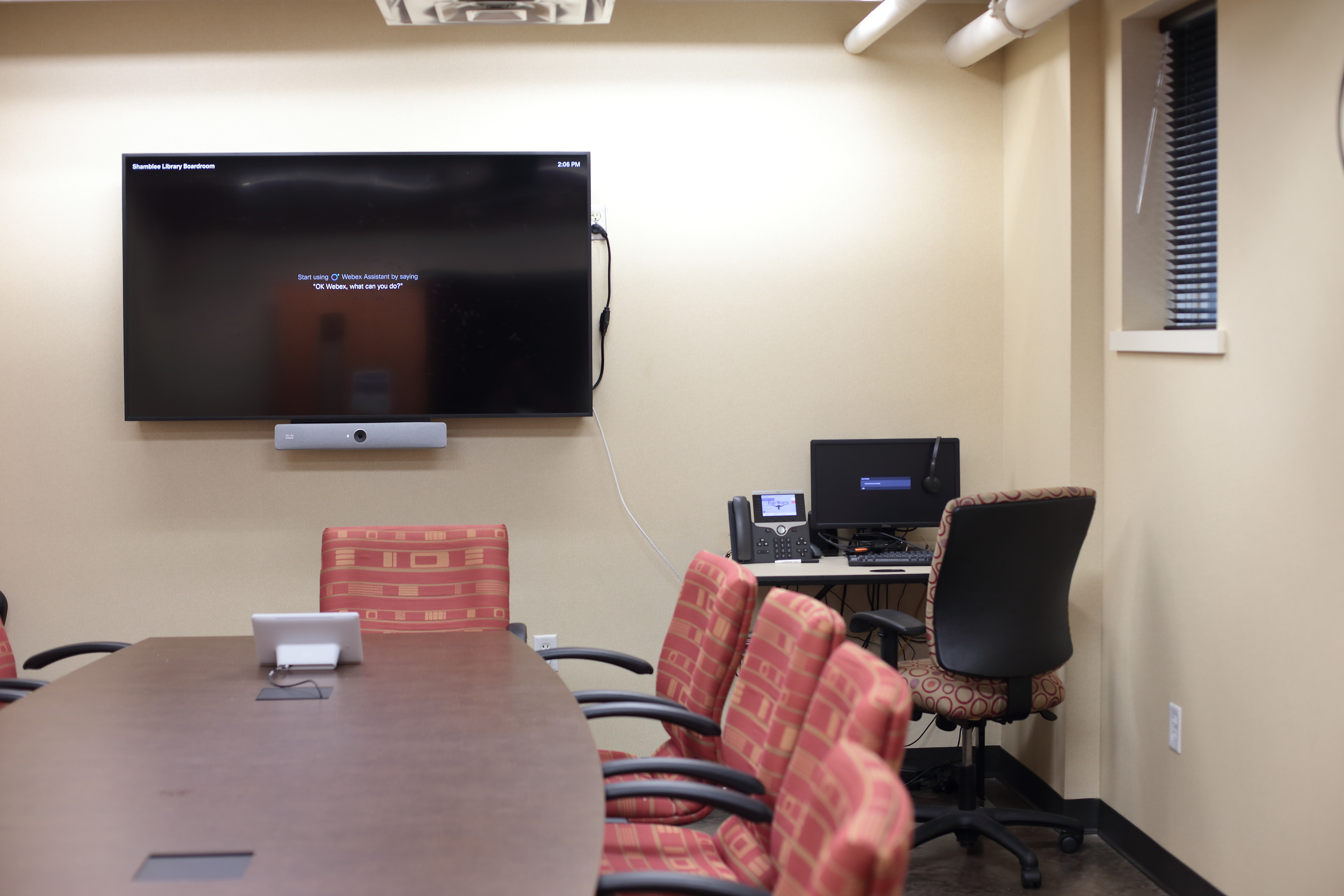 A conference room featuring a video screen, table and chairs.