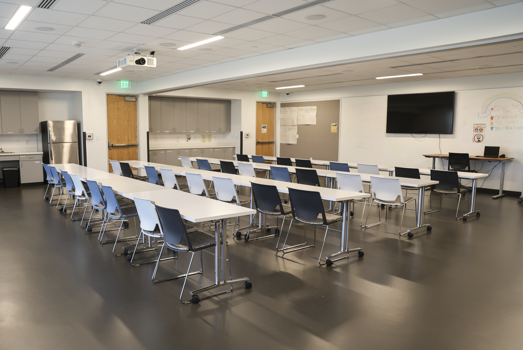 Large rental room featuring several tables with charis and a TV on the wall.