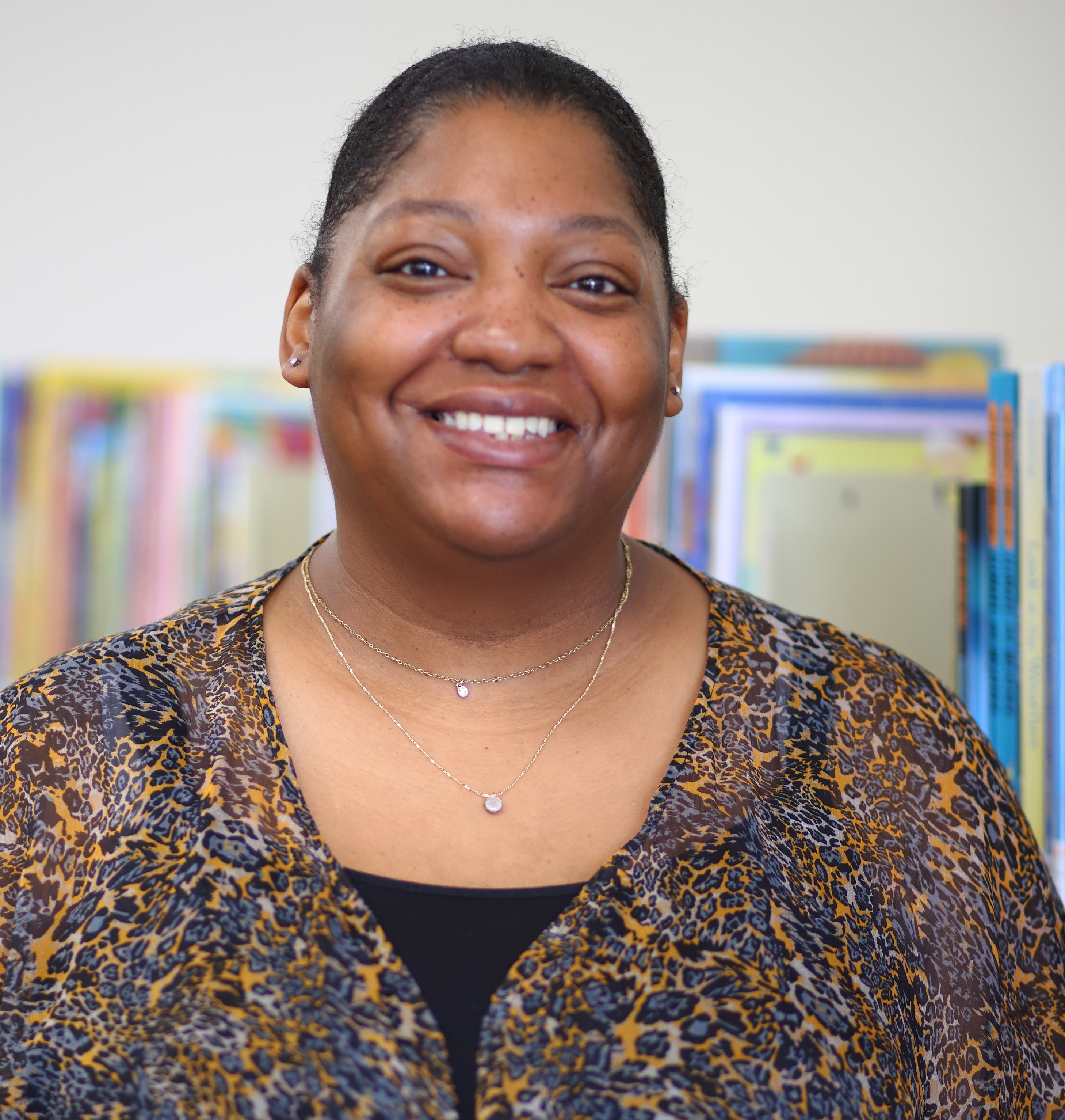 A woman poses for a photo in a library.