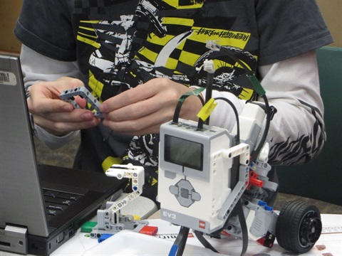 A teen works with a LEGO robotics kit at the library.