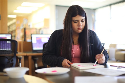 A participant in Teen Time paints her monogram. 