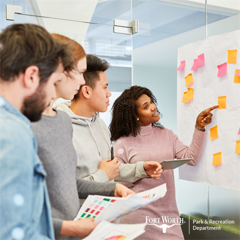 A group of people in an office reviewing post-it notes on a whiteboard