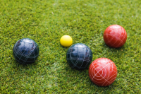 Five bocce balls sit on a field of grass. Two are blue, two are red and one is yellow.