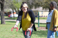 Two women play a game of horseshoes at a park.
