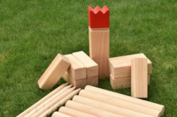 A set of wooden Kubb pieces sit on a bed of grass.