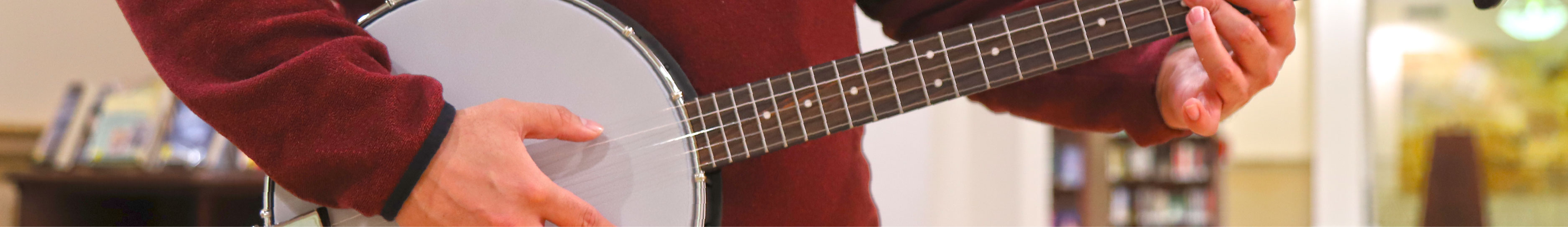 An image of a person wearing a red sweater playing a banjo.