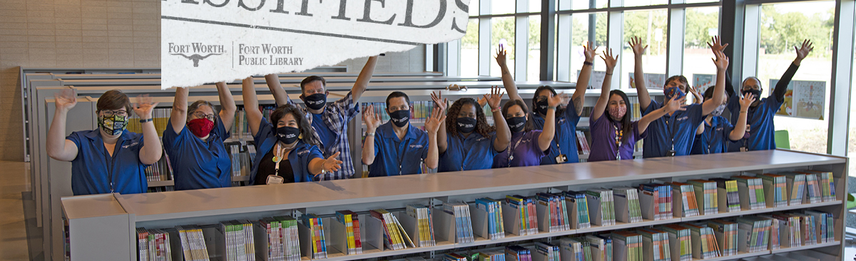 group of employees behind book case cheering with arms raised