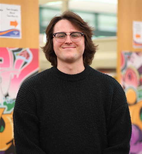 A young man poses for a photo in a library.