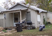 Small house with trash bin and too many items near it to tell what need to be picked up